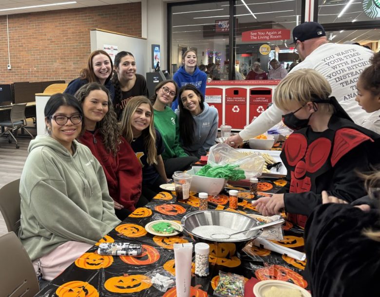 Alpha Kappa Phi sorority members hosting a cookie decorating table for local Oneonta area kids during the Halloween Carnival in SUNY Oneonta’s Hunt Union.