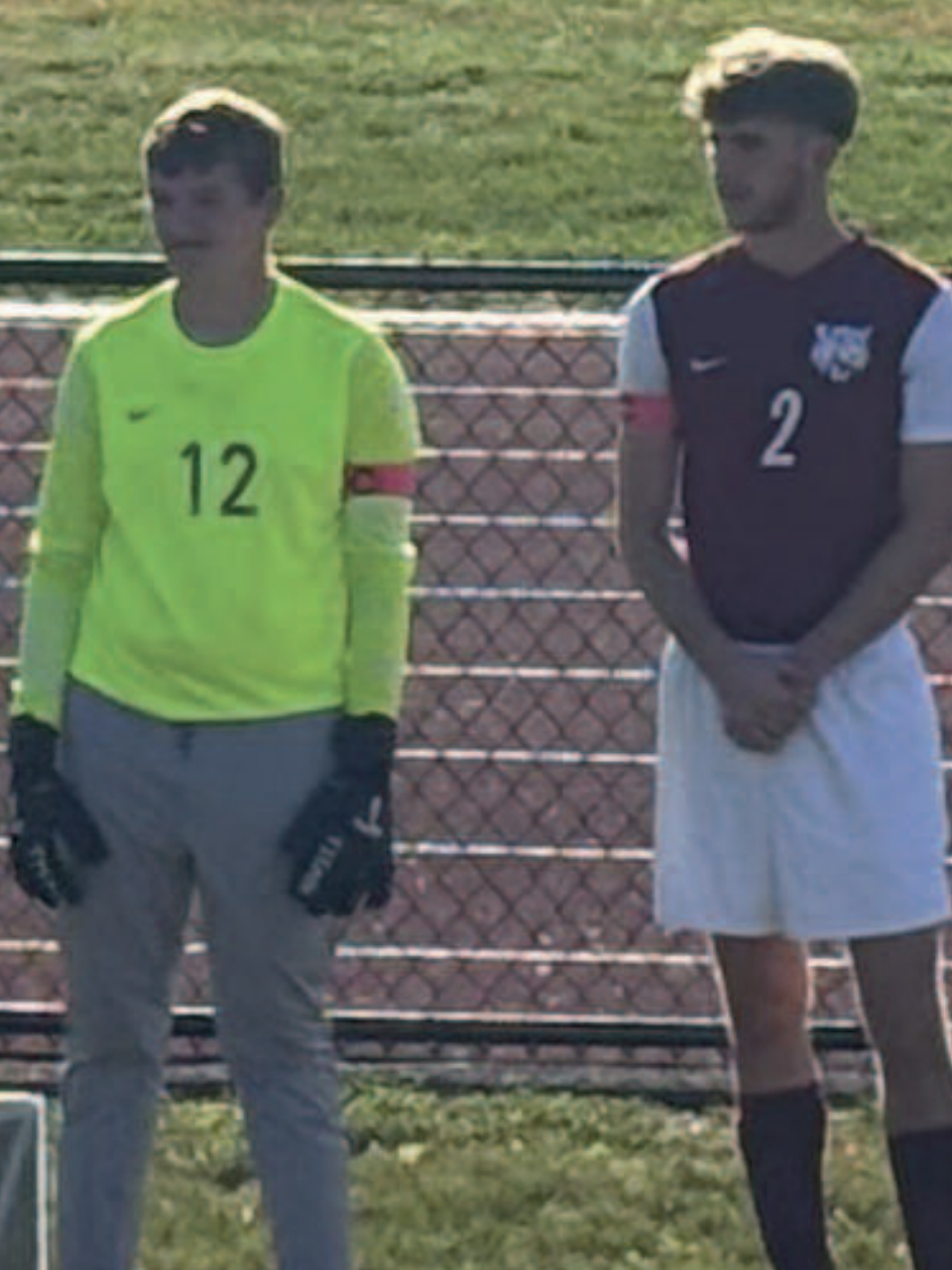 Two varsity soccer players standing next to each other.