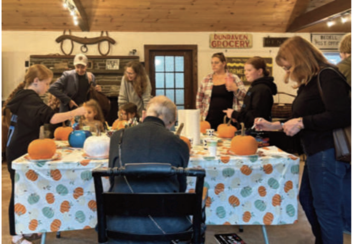 People around a table carving pumpkins.