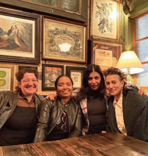 Four people standing together posing for a photo. 