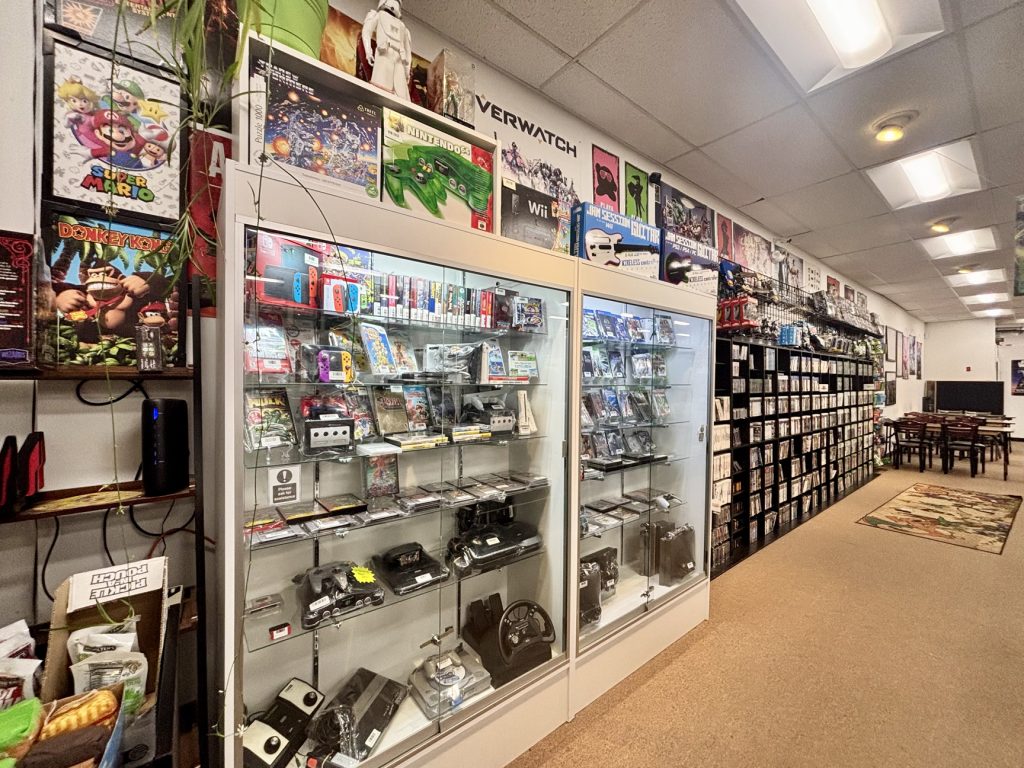 A wall of retro gaming consoles and games at Good Games.