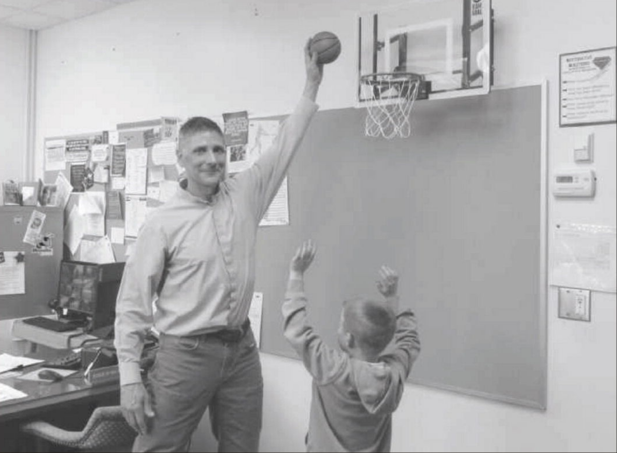 The principal and a young boy playing basketball.