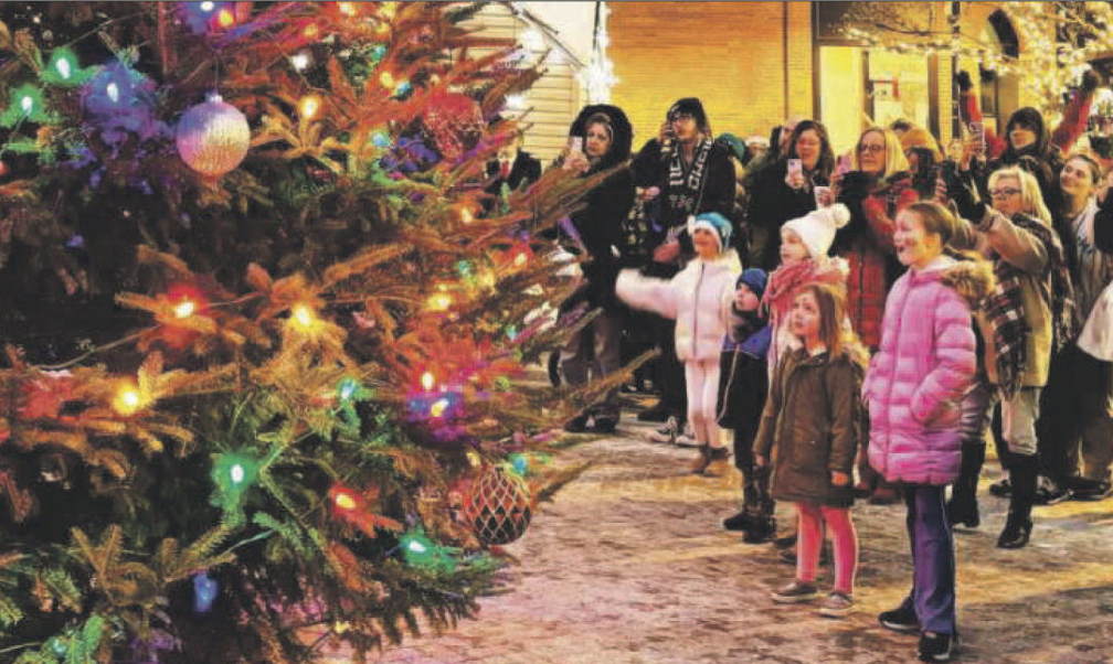 People outside around a lit up tree.